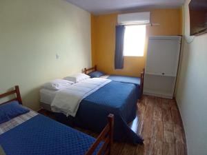 a small room with two beds and a window at Pousada São Benedito CP in Cachoeira Paulista