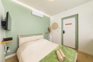 a bedroom with a white bed with a green blanket at Le Sauge - Studio climatisé - Cocon rénové in Agen