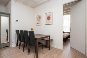 a dining room with a wooden table and black chairs at Theislandlife 4p Centrum Texel in Den Burg