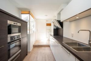 a kitchen with white cabinets and a black counter top at Theislandlife 4p Centrum Texel in Den Burg