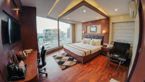 a bedroom with a bed and a desk and a television at Hotel Sawood International in Kolkata