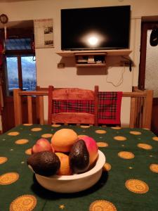 a bowl of fruit on a table with a television at The Golden Eagle - Champdepraz in Champdepraz