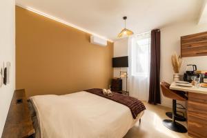 a bedroom with a bed and a desk and a window at Le Brun - T1 climatisé - Terrasse et jardin privé in Agen