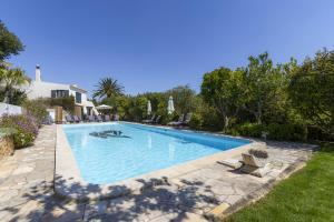 a swimming pool in a yard with chairs and trees at Nice double bedroom in beautiful Quinta - QR06 in Lagos