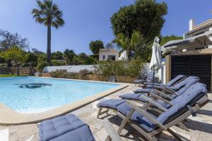 a swimming pool with lounge chairs and an umbrella at Nice double bedroom in beautiful Quinta - QR06 in Lagos