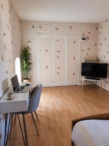 a bedroom with a desk with a laptop and a television at Logis Hotel restaurant de la Poste in Pontgibaud