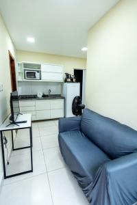a living room with a blue couch and a kitchen at Studio Completo c Wifi perto do Centro de Itabuna in Itabuna