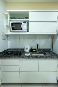 a white kitchen with a microwave and a sink at Studio Completo c Wifi perto do Centro de Itabuna in Itabuna