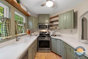 a kitchen with green cabinets and a stove top oven at Lake Geneva Escape 4BR Arcade Fire Pit and Deck in Lake Geneva