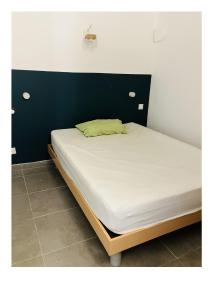 a bed with white sheets and a green pillow on it at Ile Rousse in LʼÎle-Rousse