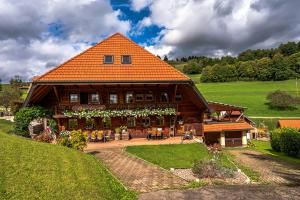 a large wooden house with an orange roof at Gästehaus Holzer Kreuz - Gästezimmer Veilchen für 2 Personen inkl Landfrühstück in Fröhnd