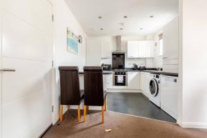 a kitchen with white cabinets and two chairs at Irvine Harbor Apartments in Irvine