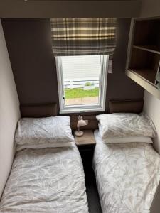 two beds in a small room with a window at Paws a while in Mainsriddle +33 photos