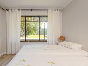 two white beds in a bedroom with a window at Ocean View 147 in Struisbaai