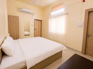 a bedroom with a white bed and a window at Hotel Shreenath Heritage in Ujjain