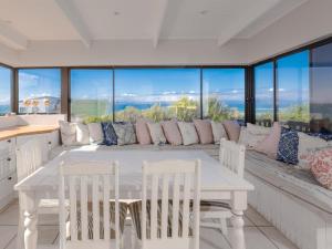 a dining room with a table and chairs and windows at Ocean View 147 in Struisbaai