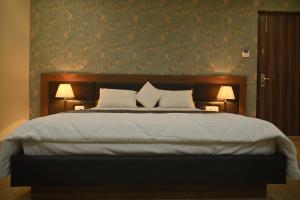 a bedroom with a large bed with two lamps at Hotel Vinayak International in Muzaffarpur