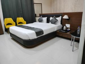 a bedroom with a bed and two yellow chairs at Hotel Vinayak International in Muzaffarpur
