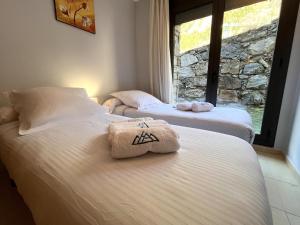 two beds with towels on them in a room with a window at AC Apartaments Saüc Canillo in Canillo