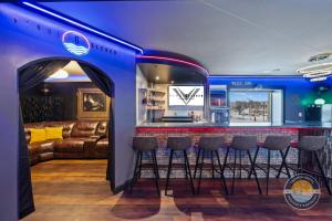 a bar in a room with a couch and stools at Event Lounge with Pool Table and Arcade in Lake Geneva