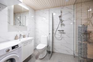 a white bathroom with a shower and a toilet at Lumi Apartments in Rovaniemi