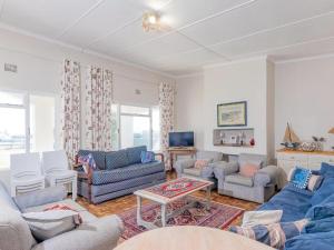 a living room with blue couches and a tv at Kusweg Oos 1 in Struisbaai