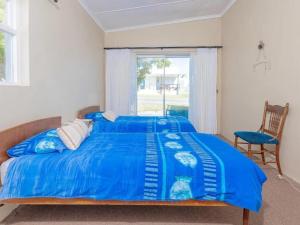 a bedroom with a blue bed and a chair at Kusweg Oos 1 in Struisbaai