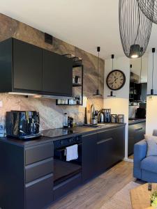 a kitchen with black cabinets and a clock on the wall at Ostoja Dębowa Studnica in Studnica