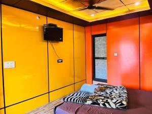 a yellow room with a bed and a tv at Hotel Dev in Kainūr