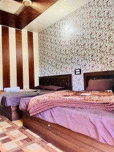 a bedroom with two beds and a wall with wallpaper at Hotel Dev in Kainūr
