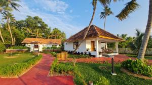 a house with a tile roof and a yard at Kaayal Luxury Villa Varkala Private Lakefront Retreat in Varkala