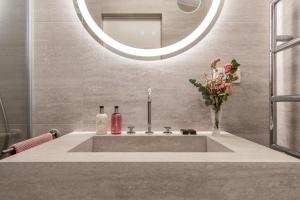 a bathroom sink with a mirror and a vase of flowers at Residence 9 in Krakow +57 photos
