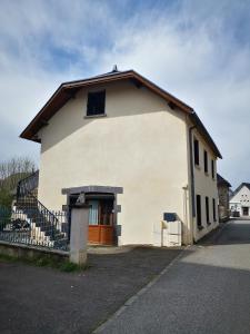 a white house with a brown door on a street at Gîtes & chambre d'Hôtes - AVEZE in Avèze