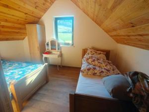 a attic bedroom with two beds and a window at Zakątek Sądrecko in Rząśnik