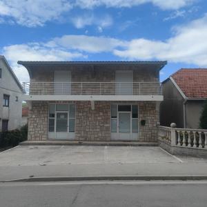 a brick house with a balcony on a street at Apartman Maša Bileća in Bileća