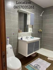 a bathroom with a toilet and a sink and a mirror at Maya location in Bejaïa