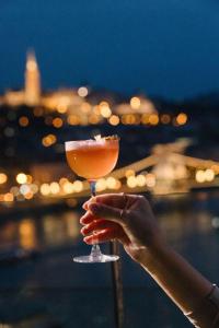 a person holding a drink with a city in the background at Budapest Marriott Hotel in Budapest