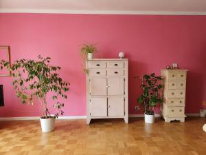 a room with a pink wall with plants and a dresser at Zimmer an der Wedel in Burgwedel