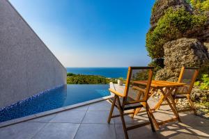 a table and chairs on a patio with a view of the ocean at Hanalee Villa Kouri in Nakijin