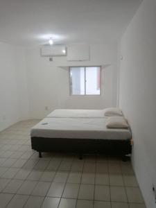 a bed in a white room with a window at Pousada Amarela in Fortaleza