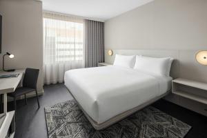 a bedroom with a large white bed and a desk at AC Hotel by Marriott Ann Arbor Downtown in Ann Arbor