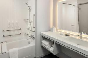a white bathroom with a sink and a tub and a mirror at AC Hotel by Marriott Ann Arbor Downtown in Ann Arbor +31 photos