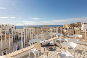 a balcony with tables and chairs and the ocean at Dimora Suite Idro in Gallipoli