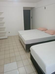 two beds in a room with a tiled floor at Pousada Amarela in Fortaleza