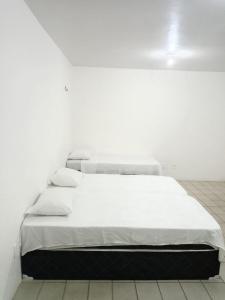 a white bed in a white room with white walls at Pousada Amarela in Fortaleza