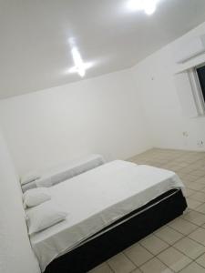 a white bed in a white room with a white wall at Pousada Amarela in Fortaleza