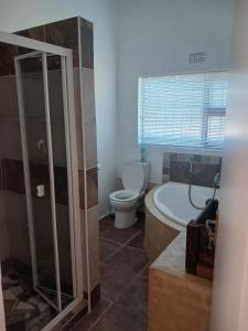 a bathroom with a bath tub and a toilet at EBB Tide Guesthouse in Velddrif +94 photos