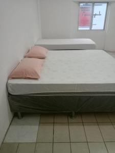 a bed with two pink pillows on it in a room at Pousada Amarela in Fortaleza