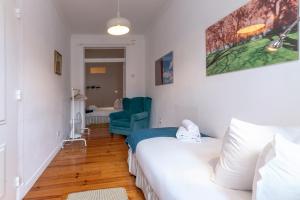 a bedroom with a white bed and a blue chair at Portas da Sé Apartments in Lisbon