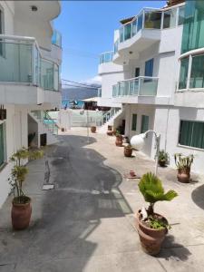 an empty street with potted plants in front of buildings at Apartamento Elizabetta 3, pé na areia in Arraial do Cabo